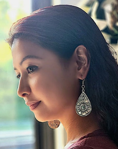 A profile view of a woman wearing intricate silver filigree teardrop earrings, which catch the light and add an elegant touch to her ensemble.