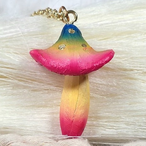 Whimsical mushroom pendant with a gradient of vibrant colors, adorned with gold specks, against a soft fluffy white background.