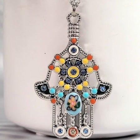 Vibrant, intricately designed Hand of Fatima pendant in silver with a mosaic of colorful beads and a central eye, representing protection and good luck.