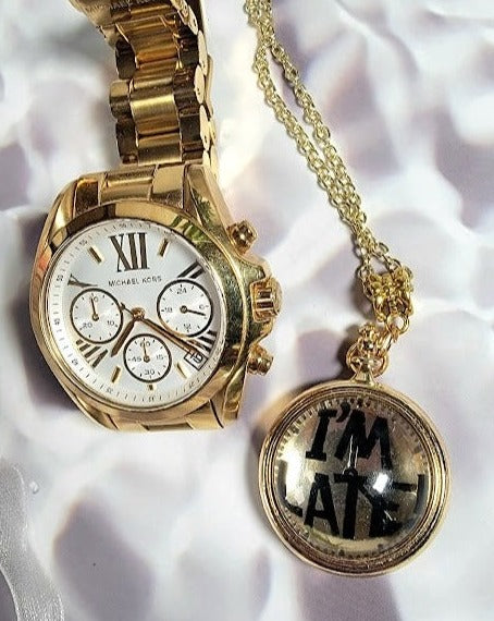 A stylish composition featuring a wristwatch alongside a whimsical "I'M LATE" pocket watch pendant. The golden tones and Roman numeral face of the wristwatch exude luxury, while the pendant adds a quirky, literary twist.