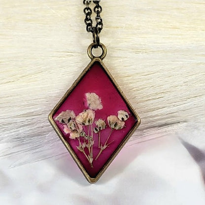 Collier floral d’inspiration vintage, bijoux d’œillets blancs triés sur le volet, pendentif en résine en forme de diamant, bijoux en toile de fond rose foncé, respectueux de l’environnement