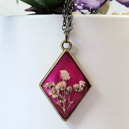 Collier floral d’inspiration vintage, bijoux d’œillets blancs triés sur le volet, pendentif en résine en forme de diamant, bijoux en toile de fond rose foncé, respectueux de l’environnement