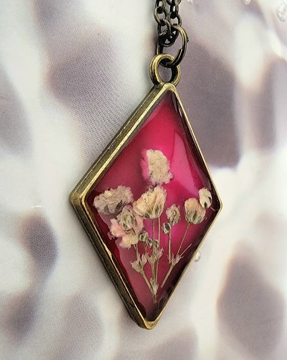 Collier floral d’inspiration vintage, bijoux d’œillets blancs triés sur le volet, pendentif en résine en forme de diamant, bijoux en toile de fond rose foncé, respectueux de l’environnement