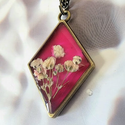 Collier floral d’inspiration vintage, bijoux d’œillets blancs triés sur le volet, pendentif en résine en forme de diamant, bijoux en toile de fond rose foncé, respectueux de l’environnement