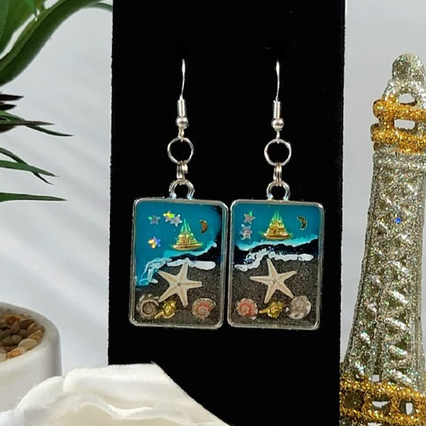 Voilier en or sur boucles d’oreilles en toile de fond bleue, bijoux du ciel nocturne nautique, souvenir de mémoire de plage, nuit étoilée à lunette argentée, ambiance de plage faite à la main