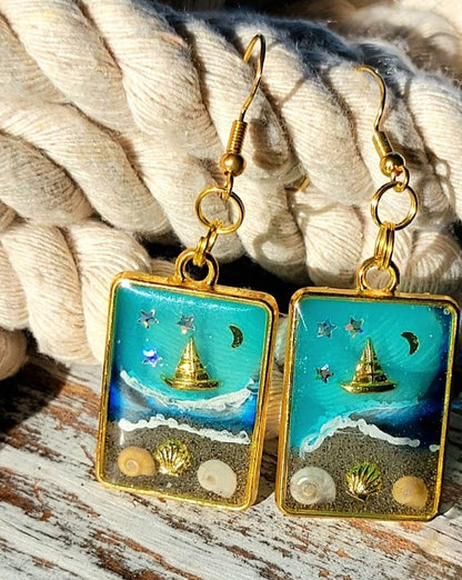 Souvenirs de plage dans un cadre doré, boucles d’oreilles de scène côtière de nuit étoilée, voilier doré sur les eaux bleues célestes, pendentif en résine océanique artisanale