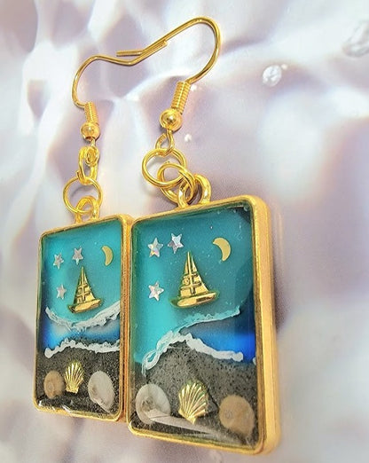 Souvenirs de plage dans un cadre doré, boucles d’oreilles de scène côtière de nuit étoilée, voilier doré sur les eaux bleues célestes, pendentif en résine océanique artisanale