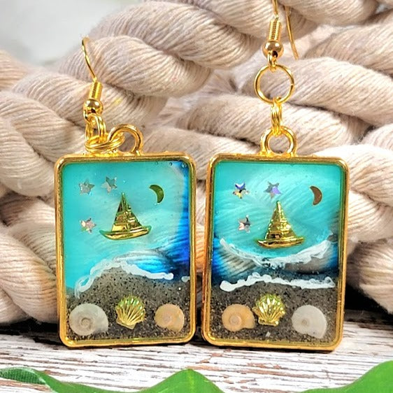 Souvenirs de plage dans un cadre doré, boucles d’oreilles de scène côtière de nuit étoilée, voilier doré sur les eaux bleues célestes, pendentif en résine océanique artisanale