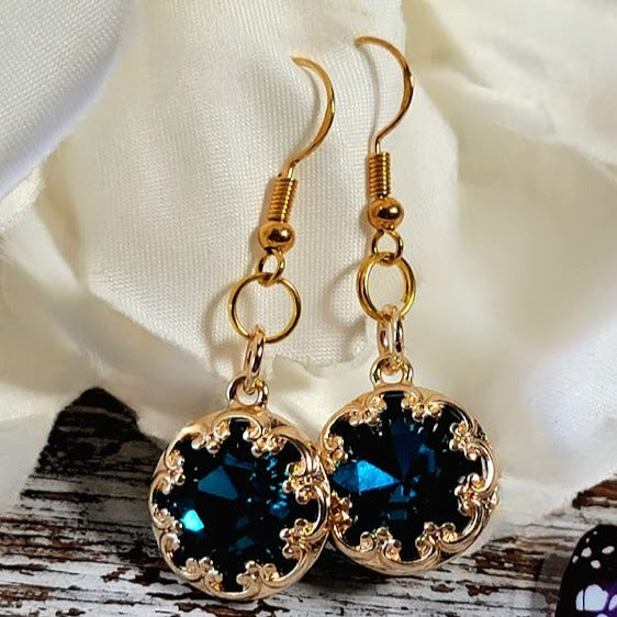 Gold-plated earrings with radiant blue crystals, surrounded by a filigree design, providing an elegant accent to any outfit.