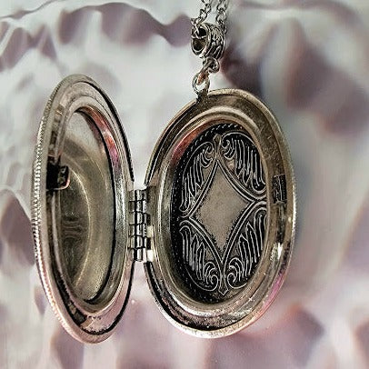 Elegant silver mermaid cameo locket open to reveal intricate engraving, combining timeless charm with a personal keepsake feature.