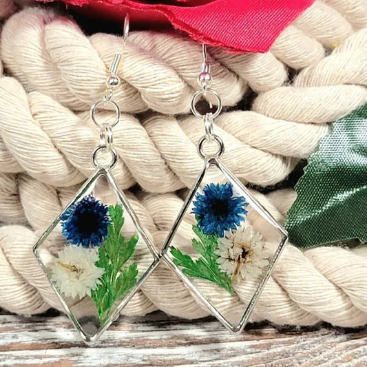 Pendientes de clavel azul y blanco, arte floral contemporáneo, follaje verde exuberante, colgante prensado naturalmente, primavera atemporal