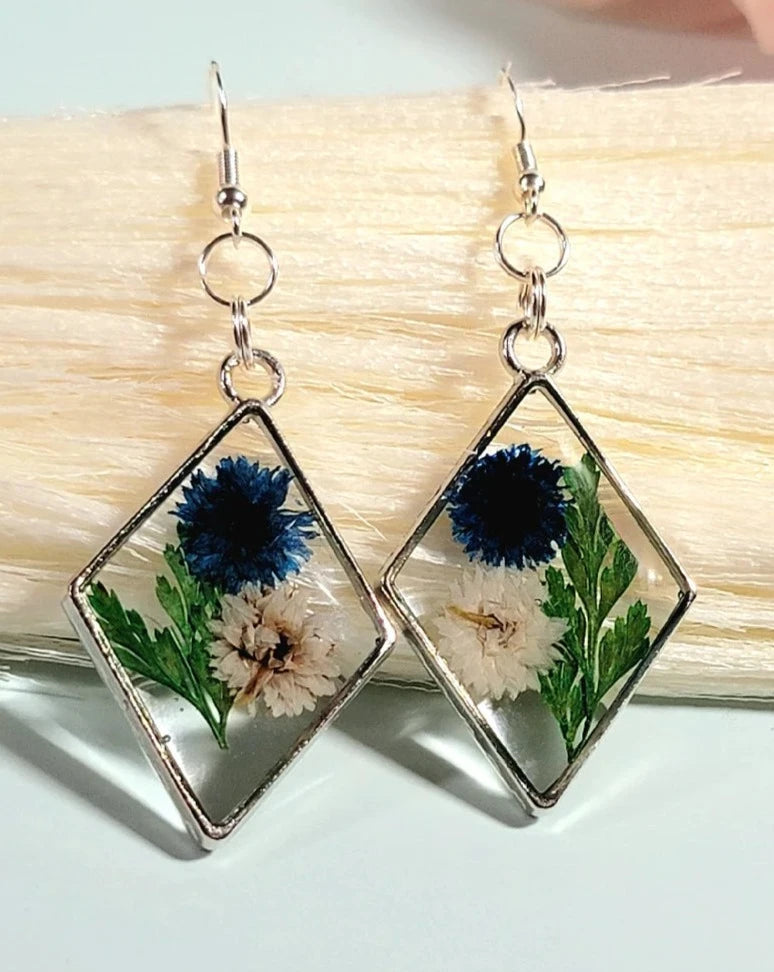 Boucles d’oreilles œillets bleus et blancs, art floral contemporain, feuillage vert luxuriant, pendentif naturellement pressé, printemps intemporel