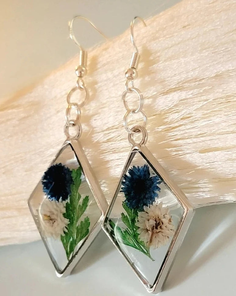 Pendientes de clavel azul y blanco, arte floral contemporáneo, follaje verde exuberante, colgante prensado naturalmente, primavera atemporal