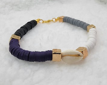 Elegant bracelet featuring purple, black, and white heishi beads, interspersed with gold-tone spacers and centered by a glossy cowrie shell.