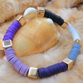 Handcrafted heishi bead bracelet in a harmonious blend of purple, black, and white with gold square spacers and a central cowrie shell for a beach-inspired vibe.