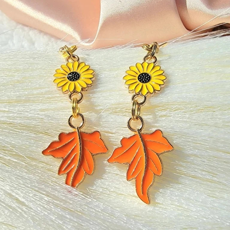 Vibrant sunflower and autumn leaf earrings crafted in brilliant yellow and orange enamel, dangling from gold-tone links, celebrate the essence of fall.