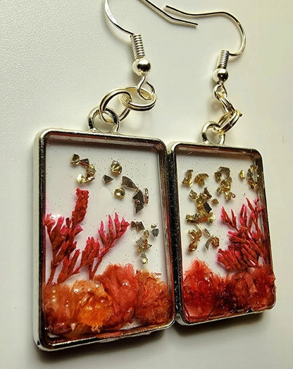 Accessoires nature avant-gardistes, petits boutons floraux dans une lunette carrée argentée, boucles d’oreilles artisanales inspirées de la nature, botanique pêche et orange