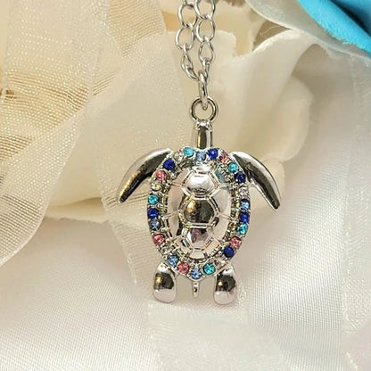 Captivating sea turtle pendant necklace, adorned with a kaleidoscope of sparkling multicolored rhinestones, set in a polished silver frame, hanging gracefully from a classic chain, a testament to marine beauty and glitz.